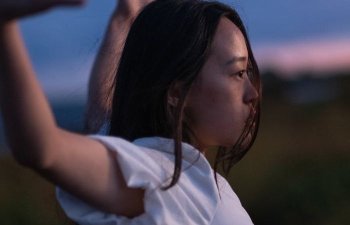 Person stretching gently outdoors with a serene background.